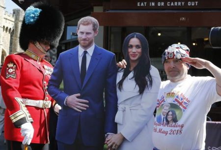 A soldier looks at a royal fan with a cardboard cutout of Britain's Prince Harry and Meghan Markle in Windsor, Tuesday, May 15, 2018. Preparations are being made in the town ahead of the wedding of Britain's Prince Harry and Meghan Markle that will take place in Windsor on Saturday May 19.