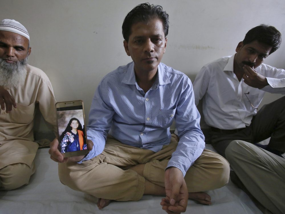 Abdul Aziz Sheikh (center), the father of Sabika Sheikh, a victim of a shooting at a Texas high school, shows a picture of his daughter in Karachi on Saturday.
