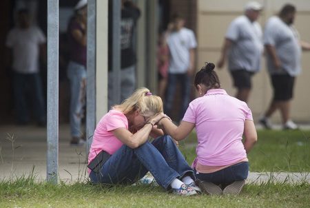 People outside a middle school set up as a reunion point for parents and students in Santa Fe, Texas on Friday, March 18, 2018 after a gunman killed at least 10 people at Santa Fe High School.