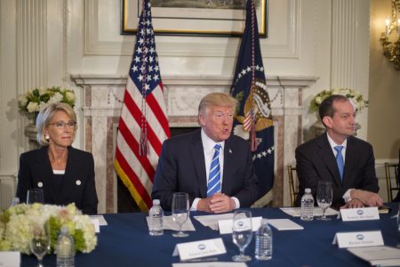 President Donald Trump, flanked by Education Secretary Betsy DeVos, left, and Labor Secretary Alexander Acosta, answers questions in August of 2017, at Trump National Golf Club in Bedminster, N.J. Today the White House announced plans to merge the two departments.