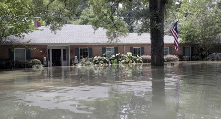 A United States flag hangs outside a flooded home in the aftermath of Hurricane Harvey, Monday, Sept. 4, 2017, near the Addicks and Barker Reservoirs in Houston.