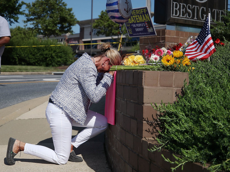 Lynne Griffin pays her respects at a makeshift memorial outside the Capital Gazette offices, one day after a gunman killed five people in its newsroom. Griffin was a journalism student under John McNamara — one of the people killed Thursday.
