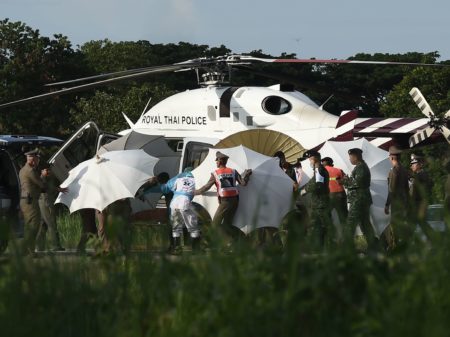 Police and military personnel use umbrellas to cover a stretcher as it is carried to a helicopter from an ambulance at a military airport in Chiang Rai, Thailand, on Monday, as rescue operations continue for those still trapped inside the cave in Khun Nam Nang Non Forest Park in the Mae Sai district.