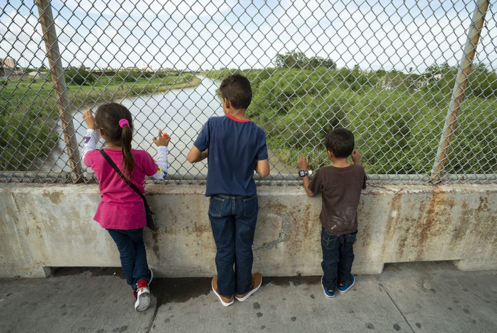 Javier Alejandro Vindel-Rodriguez (center) looks down at the Rio Grande with his siblings, Yenci (left) and Jesus Samuel on Sunday, June 24, 2018. Their family left Honduras in January, and have slowly made their way to Matamoros.  