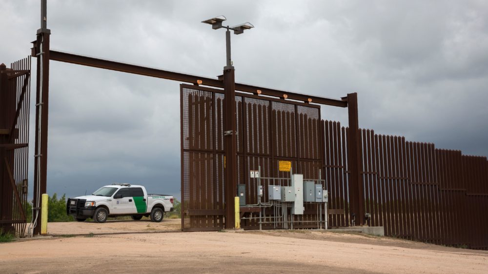 A U.S. Border Patrol agent keeps watch at a gate on the U.S.-Mexico border fence near San Benito, Texas.
