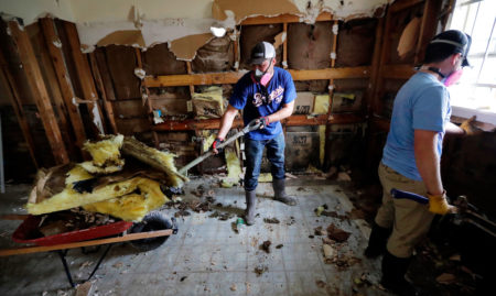 FILE - In this Sept. 4, 2017, file photo, volunteers Brock Warnick, right, and Colten Roberts remove drywall and insulation from a home which was damaged by floodwaters in the aftermath of Hurricane Harvey in Houston. Advocacy groups say Texas is poised to unfairly distribute $5 billion in federal funding provided for housing repairs following Hurricane Harvey, prioritizing wealthy homeowners over poor and working class victims in ways that could constitute racial discrimination. (AP Photo/, File)