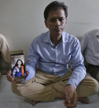 Abdul Aziz Sheikh (center), the father of Sabika Sheikh, a victim of a shooting at a Texas high school, shows a picture of his daughter in Karachi.