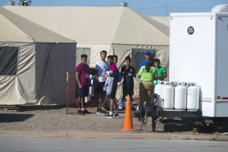 In this Nov. 15, 2018 photo provided by Ivan Pierre Aguirre, migrant teens held inside the Tornillo detention camp look at protestors waving at them outside the fences surrounding the facility in Tornillo, Texas. The Trump administration announced in June 2018 that it would open the temporary shelter for up to 360 migrant children in this isolated corner of the Texas desert. Less than six months later, the facility has expanded into a detention camp holding thousands of teenagers - and it shows every sign of becoming more permanent.  (Ivan Pierre Aguirre via AP)