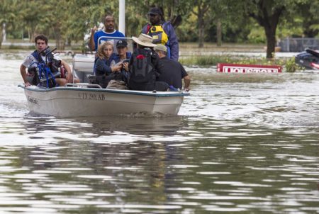 Evacuees flee flooding in a boat with a nearly submerged Houston sign behind them, on Aug, 29, 2017. Hurricane Harvey made landfall as a Category 4 storm with winds of 130 miles per hour four days prior.