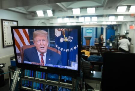 President Trump appears on a monitor in the Press Briefing Room of the White House on Tuesday.