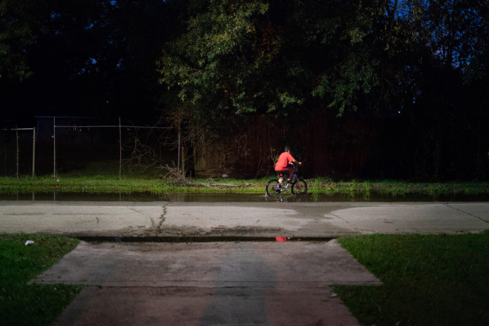 A boy rides his bike through still water after a thunderstorm in the Lakewood area of East Houston, which flooded during Hurricane Harvey.