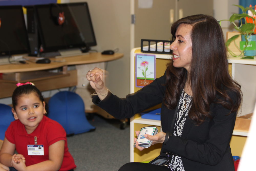 Bilingual pre-K teacher Atanea Raptis coaches her students on their letter sounds and numbers.