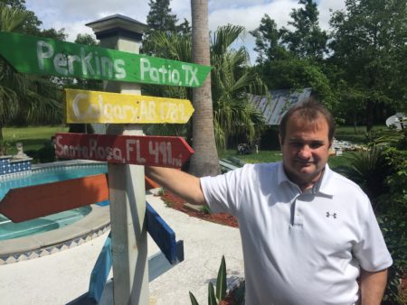 Steve Perkins stands outside his home in Santa Fe. His wife, Glenda Ann, loved to travel and they had this post made to mark the distance to her favorite spots.