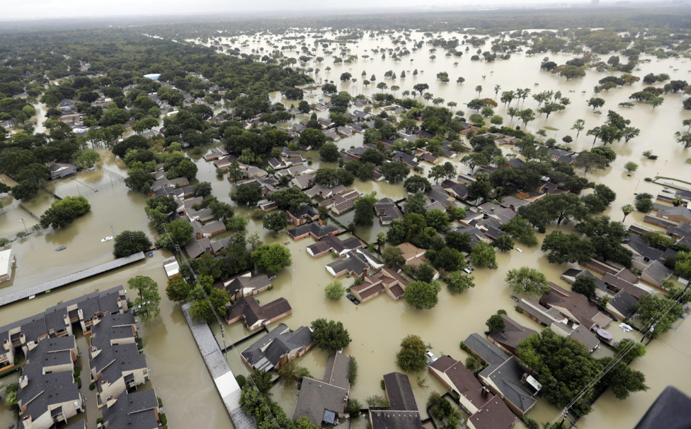 In this Aug. 29, 2017 photo, water from Addicks Reservoir flows into neighborhoods from floodwaters brought on by Tropical Storm Harvey in Houston. Harris County commissioners have voted to ask the federal government for a $17 million grant to purchase 104 homes at the highest risk of flooding. The decision came even as more than 1,000 residents have called the Flood Control District in recent days to request buyouts of their Hurricane Harvey flood-damaged homes. 