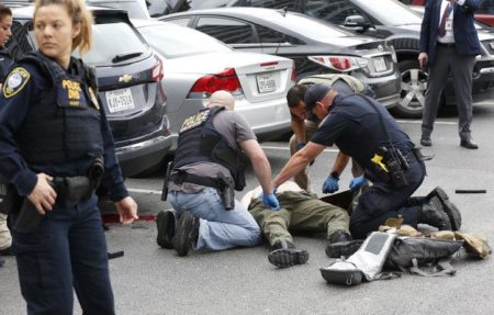Law enforcement officers attend to an injured shooter in a parking lot after he fired shots at the Earle Cabell Federal Building in downtown Dallas on Monday.