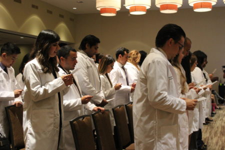 During a "Long White Coat Ceremony" held on June 28, 2019, at the University of Houston, medical school graduates recite the Hippocratic oath before beginning their residency, a traditional rite of passage for doctors entering the profession.