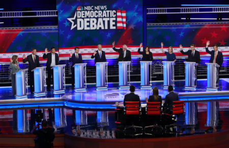 In this June 27, 2019 photo, Democratic presidential candidates, author Marianne Williamson, former Colorado Gov. John Hickenlooper, entrepreneur Andrew Yang, South Bend Mayor Pete Buttigieg, former Vice President Joe Biden, Sen. Bernie Sanders, I-Vt., Sen. Kamala Harris, D-Calif., Sen. Kirsten Gillibrand, D-N.Y., Colorado Sen. Michael Bennet, and Rep. Eric Swalwell, D-Calif., raise their hands when asked if they would provide healthcare for undocumented immigrants, during the Democratic primary debate hosted by NBC News at the Adrienne Arsht Center for the Performing Arts in Miami. (AP Photo/Wilfredo Lee)