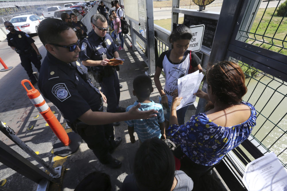 In this July 17, 2019, file photo, a United States Customs and Border Protection Officer checks the documents of migrants before being taken to apply for asylum in the United States, on International Bridge 1 in Nuevo Laredo, Mexico. On Wednesday, July 24, 2019, a federal judge in San Francisco will hear arguments in a challenge to the new Trump Administration policy that requires asylum-seekers who cross through a third country headed to the U.S. to first apply for protection in that other country. The lawsuit was brought by the American Civil Liberties Union, Southern Poverty Law Center, and Center for Constitutional Rights as they seek a temporary restraining order to block the plan.