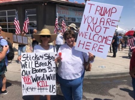Two protesters hold signs criticizing President Donald Trump's visit to El Paso on Aug. 7, 2019, to meet with first responders and survivors of the mass shooting that occurred on Aug. 3, 2019.