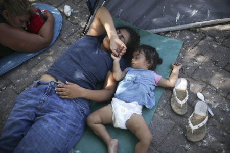 In this Aug. 1, 2019, photo, migrants rest near a Mexican immigration center where migrants set up camp in Matamoros, Mexico. Turning Mexican border cities into waiting rooms for asylum seekers may be the Trump administration’s most forceful response yet to a surge of migrants, many of them Central American families.