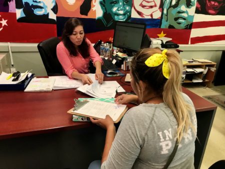 Non-profit benefits navigator Angie Ochoa, with ECHOS, helps a Salvadoran construction worker in Houston sign her daughter up for food stamps and CHIP. The woman previously withdrew her daughter from benefits due to immigration concerns (2019).