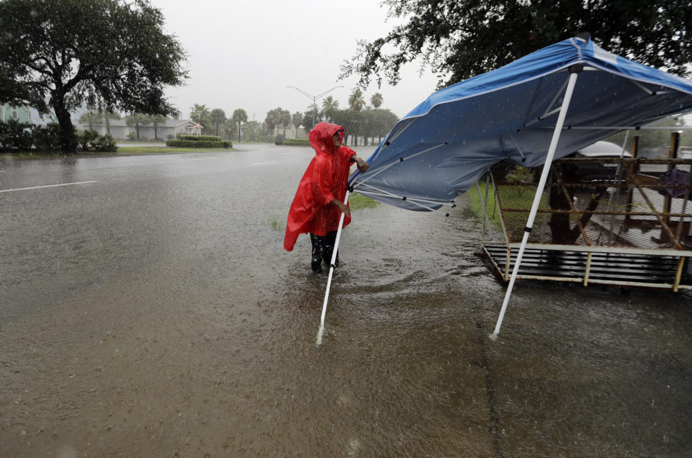 Jesus Escavado takes down a tent as heavy rains from Tropical Depression Imelda flood the streets in Galveston, Texas, Wednesday, Sept. 18, 2019.