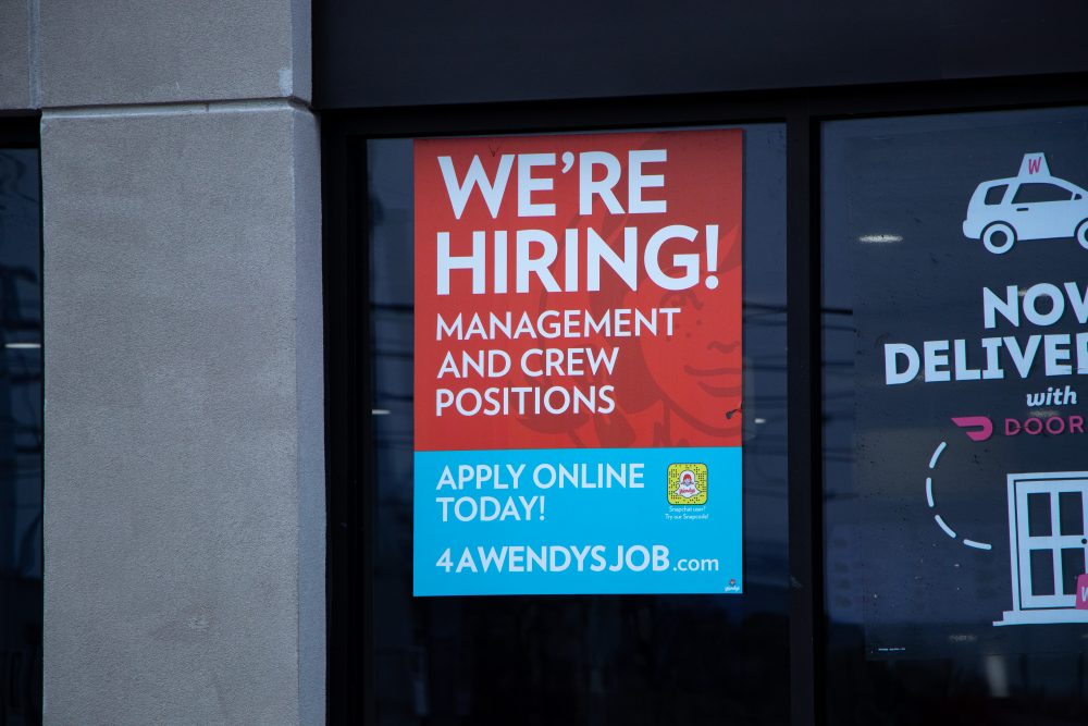 A sign on a business announcing it is hiring for new positions.