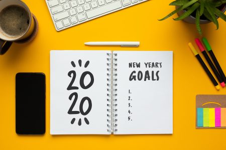 Stock photo of 2020 new year notebook with list of goals and objects on yellow background