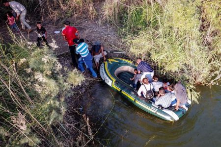 In this June 2019 file photo, agroup of 11 migrants, guided by two smugglers crosses the Rio Grande in rafts near an area known as Rincon, in South McAllen, TX.