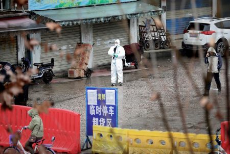 A worker in a protective suit stands near the closed seafood market in Wuhan, China.