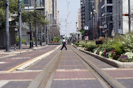 A man crosses a nearly empty Main Street in downtown Houston, Tuesday, March 24, 2020.