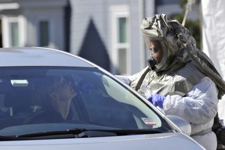 A medical professional takes samples from person at a drive-through coronavirus testing lab set up at Somerville Hospital in Somerville, Mass., on Wednesday.