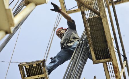 An oil well worker balances atop the rig while guiding pipes into an oil well in Talpa, Texas, Friday, May 23, 2008.