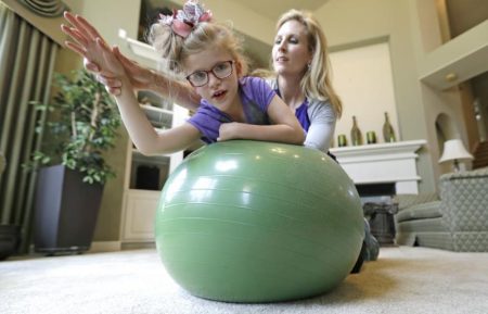 In this 2017 photo, Stacey English works on balance and core strength with her 7-year-old daughter, Addison, in Houston. Parents are stepping in even more during the pandemic since therapists can't work with students with disabilities in person.