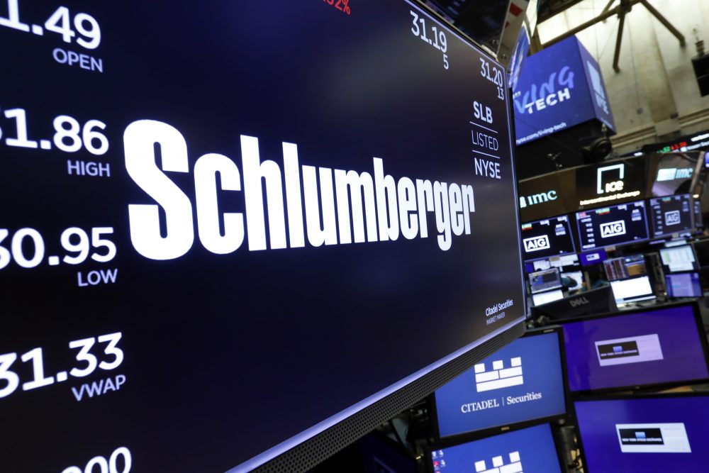 The logo for Schlumberger appears above a trading post on the floor of the New York Stock Exchange.