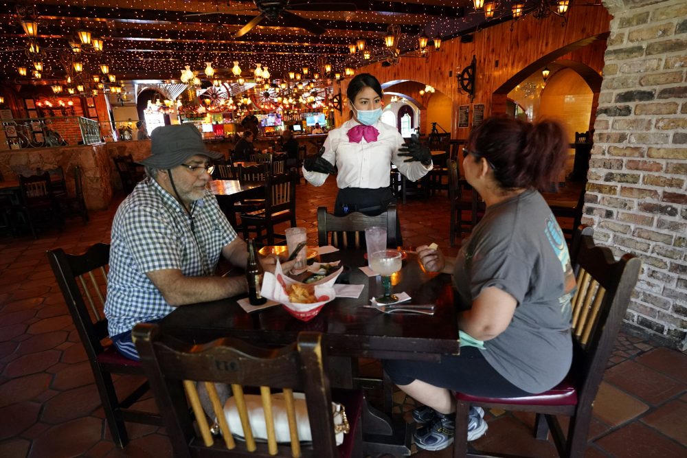 Waitress Fatima Hernandez, center, talks with Lulu Salcido, right, and Hamid Farzam at El Tiempo Cantina Friday, May 1, 2020, in Houston.