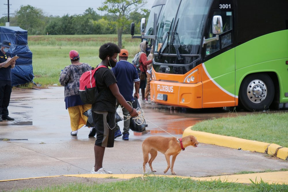 An evacuee and his dog wait to board a bus at the Robert A. “Bob” Bowers Civic Center in Port Arthur as Hurricane Laura approached the Gulf Coast on Aug. 26, 2020.