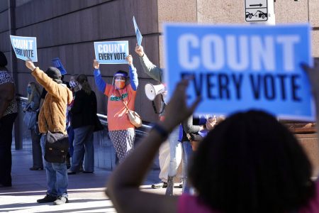 Demonstrators stand across the street from the federal courthouse in Houston, Monday, Nov. 2, 2020, before a hearing in federal court involving drive-thru ballots cast in Harris County. The lawsuit was brought by conservative Texas activists, who have railed against expanded voting access in Harris County, in an effort to invalidate nearly 127,000 votes in Houston because the ballots were cast at drive-thru polling centers established during the pandemic.