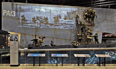 Three New York Army National Guard Soldiers posed for figures that inhabit this exhibit of a Higgins Boat landing craft loading up for the landings in Normandy on D-Day, June 6, 1944, at the National Museum of the United States Army. Major Kevin Vilardo, served as the model for the photographer in the stern, while 1st Lt. Sam Gerdt modeled the Soldier waiting at the side of the boat. Sgt. 1st Class Nick Archibald served as the model for one of the Soldiers climbing down the cargo net. The museum opens to the public on Nov. 11, 2020.