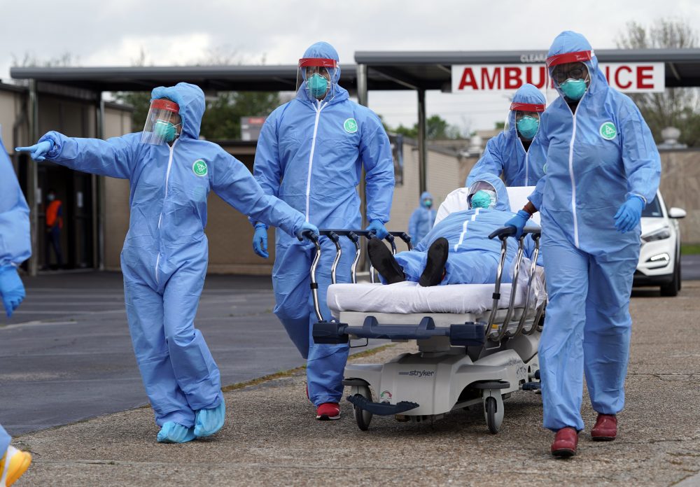 A woman is taken on a stretcher by healthcare professionals into the United Memorial Medical Center after going through testing for COVID-19 Thursday, March 19, 2020, in Houston. People were lined up in their cars in a line that stretched over two miles to be tested in the drive-thru testing for coronavirus.