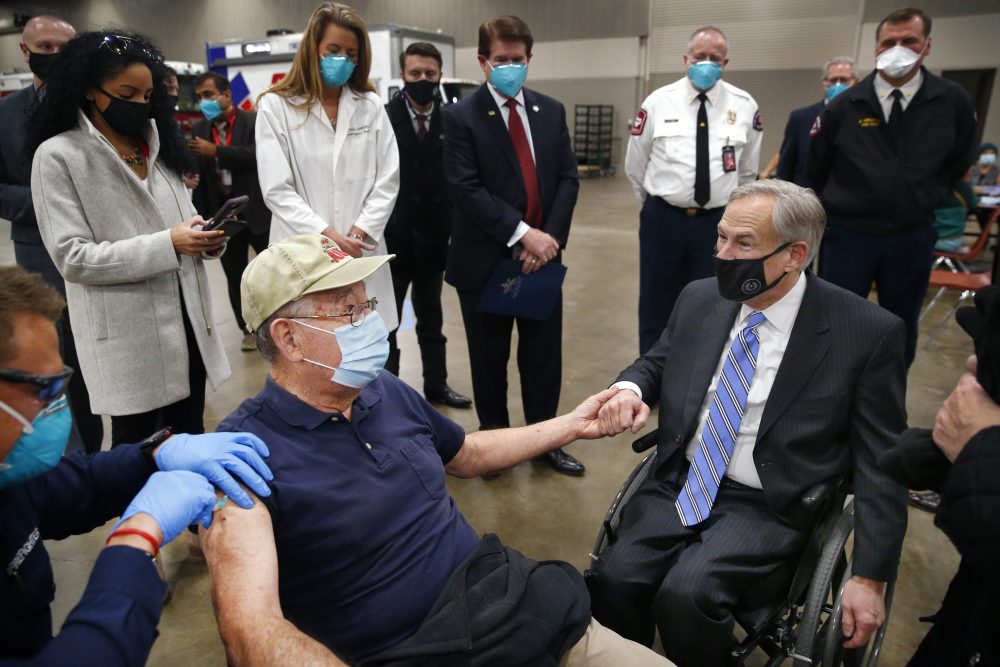 Texas Governor Greg Abbott, right, holds the hand of 86 yr-old Al Godfrey of Arlington as he receives his COVID-19 shot at a mass vaccination site inside Esports Stadium Arlington &amp; Expo Center in Arlington, Texas, Monday, Jan. 11, 2021. Earlier Abbott met with local and state officials for a briefing and then provided an update on COVID-19 vaccine efforts in Texas. 
