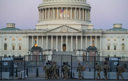 Members of the National Guard walk beside barbed wire fencing on U.S. Capitol grounds at sunrise on Monday ahead of Tuesday's Senate impeachment trial.