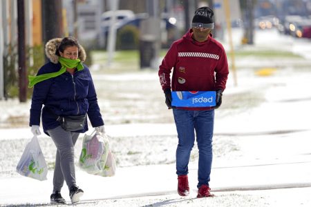 Lia Ubidia, left, and her son, Andrew Velarde, carry groceries as they walk home through the snow Monday, Feb. 15, 2021, in Houston. A frigid blast of winter weather across the U.S. plunged Texas into an unusually icy emergency Monday that knocked out power to more than 2 million people and shut down grocery stores and dangerously snowy roads.