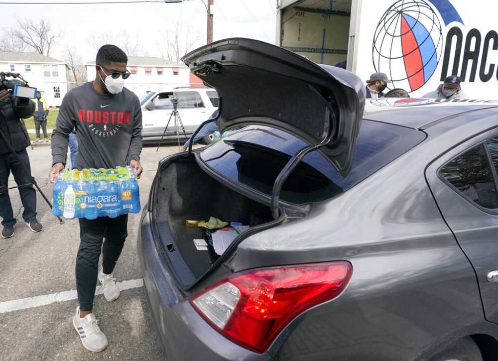 A volunteer loads donated water into the trunk of a car at a distribution site, Thursday, Feb. 18, 2021, in Houston. Houston and several surrounding cities are under a boil water notice as many residents are still without running water in their homes. 