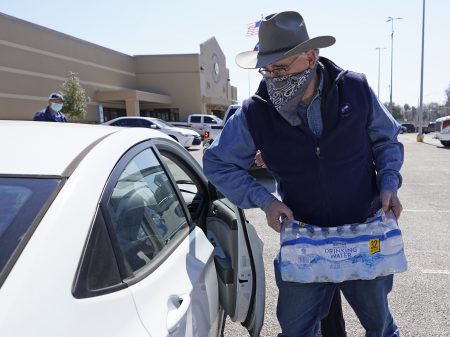 Harris County Precint 4 Commissioner Jack Cagle hands out water at a distribution site Friday, Feb. 19, 2021, in Houston. The city remains under a boil water notice as many residents lack water at home due to frozen or broken pipes.