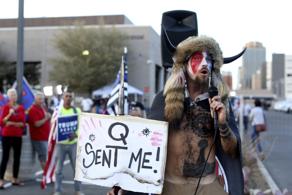 FILE - In this Nov. 5, 2020, file photo, Jacob Anthony Chansley, who also goes by the name Jake Angeli, a Qanon believer speaks to a crowd of President Donald Trump supporters outside of the Maricopa County Recorder's Office where votes in the general election are being counted, in Phoenix. Some followers of the QAnon conspiracy theory are now turning to online support groups and even therapy to help them move on, now that it's clear Trump's presidency is over.