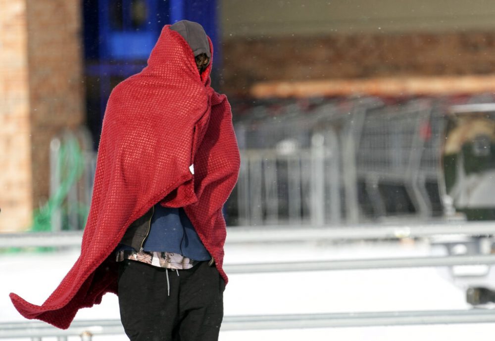 FILE: A man peers out from under a blanket while trying to stay warm in below freezing temperatures Monday, Feb. 15, 2021, in Houston. 