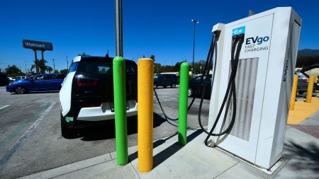 An Electric Vehicle (EV) is plugged in for a charge at EV charging stations in a Walmart parking lot in Duarte, California on September 14, 2018. - With almost half the greenhouse gas emissions coming from transportation, California has encouraged the adoption of zero-emission vehicles, which includes expanding the charging stations network and offering rebates that lower the price of new cars by thousands of dollars.