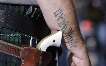 In this Jan. 26, 2015 file photo, a supporter of open carry gun laws, wears a pistol as he prepares for a rally in support of open carry gun laws at the Capitol, in Austin, Texas. Texas is still sorting out where firearms are allowed, and where they're not, more than a year after Republican Gov. Greg Abbott signed a suite of laws that vastly expanded gun rights.