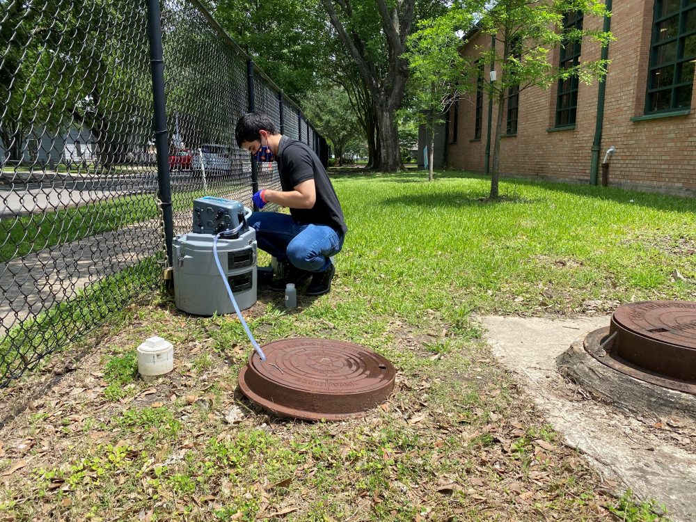 Braulio Garcia, an environmental investigator with the city’s Health Department, collects a sewage sample from a sampling well at Golfcrest Elementary School. It's part of the city's wastewater testing program that's used to help detect coronavirus outbreaks. 